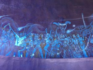On the left side, a music drenched, troubled, teenage girl envelops everything in blue musical energy. The whole scene appears as if it is levitating in space. Figures of teenagers dancing,  singing, going wild, making out, while others find themselves alone, isolated among the multitudes, unable to find their place.